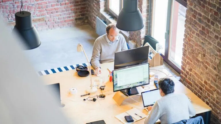 Oficinas modernas con empleados trabajando y gráficos de sueldos en pantalla simbolizando transparencia salarial en startups tecnológicas