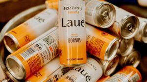 Latas de Laué Frizzante apiladas en un bowl metálico, con una lata en posición vertical al centro para mostrar claramente el diseño del producto.