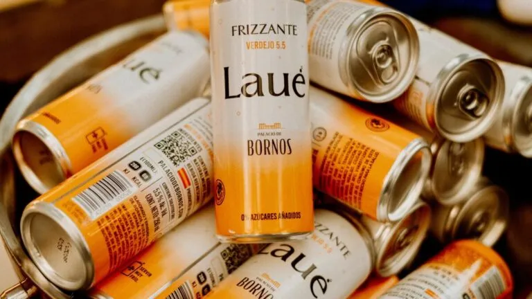 Latas de Laué Frizzante apiladas en un bowl metálico, con una lata en posición vertical al centro para mostrar claramente el diseño del producto.