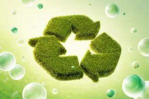 Símbolo de reciclaje cubierto de pasto, representando economía circular e innovación sostenible en el sur global