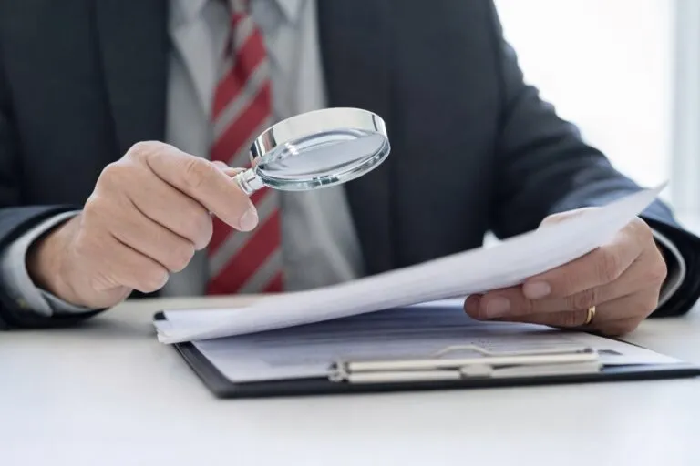 Ejecutivo revisando documentos con lupa como parte del cumplimiento de evidencia fiscal exigido por el SAT en 2026