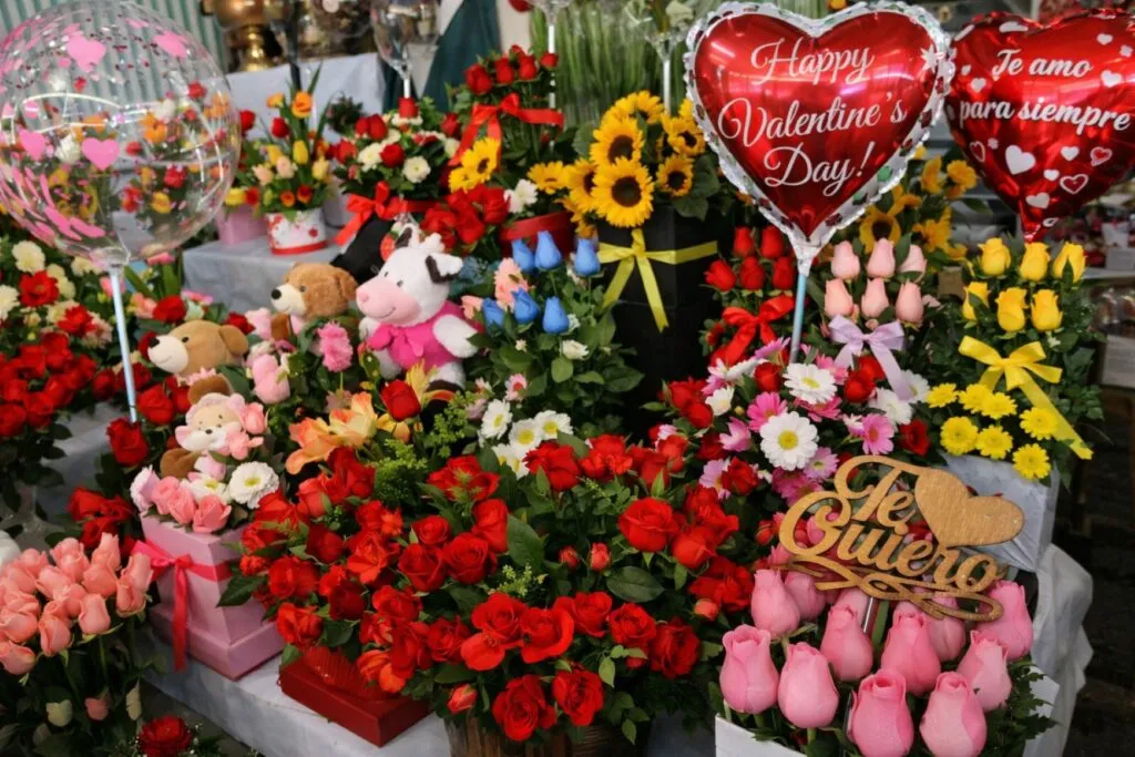 Pareja comprando flores y chocolates en una tienda durante el Día del Amor y la Amistad, reflejando derrama económica