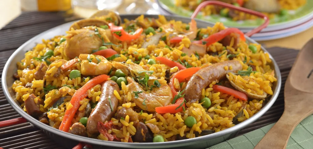 Paella tradicional española preparada en una gran sartén con arroz, mariscos y azafrán.