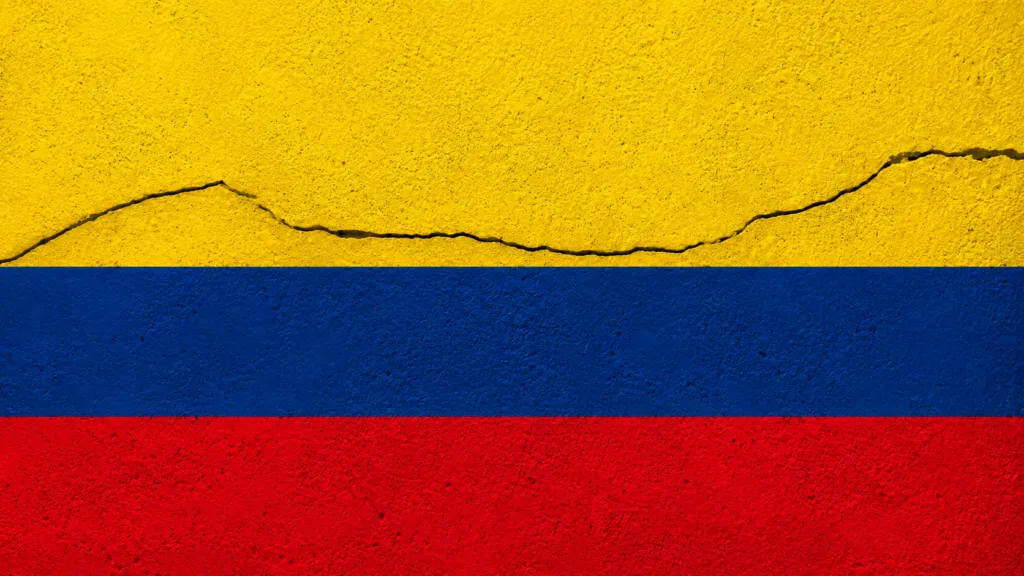 Bandera de Colombia sobre una superficie con una grieta que representa el impacto de un sismo