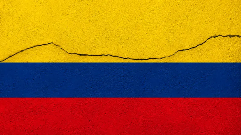 Bandera de Colombia sobre una superficie con una grieta que representa el impacto de un sismo