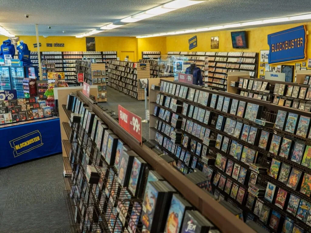 Fachada de un Blockbuster clásico con clientes entrando a rentar películas y videojuegos.