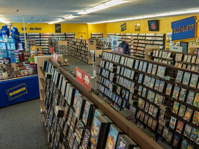 Fachada de un Blockbuster clásico con clientes entrando a rentar películas y videojuegos.