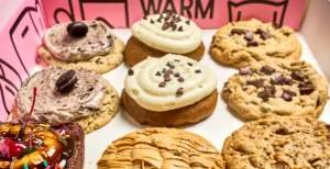 Exterior de Crumbl Cookies en Roma Norte con clientes haciendo fila y las características cajas rosas.
